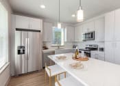 Thumbnail 4 of 23 - Dog-Friendly Apartments In Daytona Beach - Madison Pointe - Kitchen With Sleek White Cabinets, Island With Barstools, And Stainless Steel Appliances.