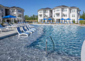 Thumbnail 54 of 54 - a large pool with blue chairs and a building in the background