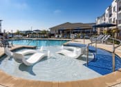 Thumbnail 12 of 60 - a resort style swimming pool with white chaise lounge chairs