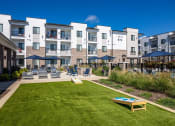 Thumbnail 18 of 60 - an exterior view of an apartment building with a lawn and a fire pit