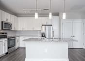 Thumbnail 32 of 48 - A modern kitchen with white cabinets and a central island.
