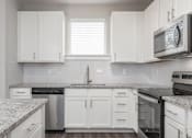 Thumbnail 29 of 48 - A kitchen with white cabinets and a granite countertop.