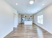 Thumbnail 33 of 40 - an empty open-concept living room and kitchen with white walls and wood floors