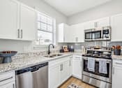 Thumbnail 2 of 59 - A kitchen with white cabinets and stainless steel appliances.