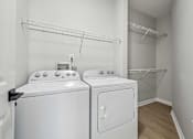 Thumbnail 11 of 59 - A white washing machine and dryer in a laundry room.