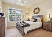 Thumbnail 10 of 42 - A bedroom with a large bed, a window with blinds, and a ceiling fan.