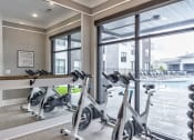 Thumbnail 8 of 25 - a gym with exercise bikes and a window view of a pool