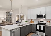 Thumbnail 20 of 49 - a kitchen with white cabinets and a large island with a sink and a dishwasher