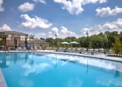 Thumbnail 25 of 46 - a swimming pool with chaise lounge chairs and umbrellas with a building in the background