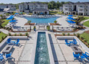 Thumbnail 17 of 54 - a swimming pool with lounge chairs and umbrellas in front of an apartment complex