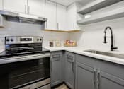 Thumbnail 4 of 28 - A modern kitchen with a stove, sink, and cabinets.
