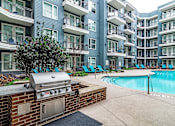 Thumbnail 24 of 26 - a barbecue grill sits next to a swimming pool in front of an apartment building