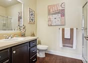 Thumbnail 13 of 42 - A bathroom with a toilet, sink, and a painting on the wall.