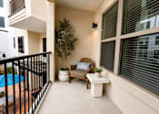 Thumbnail 12 of 41 - A balcony with a chair, table, and potted plant.