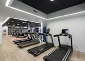 Thumbnail 27 of 36 - A gym with treadmills and elliptical machines.