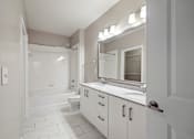 Thumbnail 16 of 36 - A white bathroom with a tub, sink, and mirror.