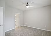 Thumbnail 13 of 36 - A room with a ceiling fan and carpeted floor.