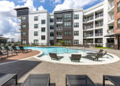 Thumbnail 23 of 25 - a swimming pool with lounge chairs in front of an apartment building