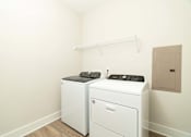 Thumbnail 21 of 43 - A white washing machine and dryer in a small laundry room.