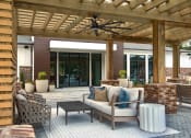 Thumbnail 32 of 46 - 2 -Bedroom Apartments in Norcross, GA - The Darnell - Poolside Outdoor Lounge Area Under a Pergola with Area Rug, Couch, Armchair, Coffee Table, and Overhead Fan