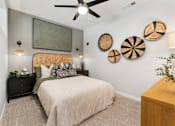 Thumbnail 20 of 34 - One-Bedroom Luxury Apartments in Huntsville, AL - The Arcadia - Bedroom with Plush Carpeting, Bed, Nightstands with Drawers, Dresser, Wall Decorations, and Ceiling Fan.