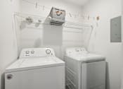 Thumbnail 9 of 28 - A white washing machine and dryer in a small laundry room.