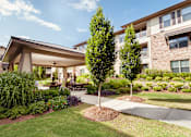 Thumbnail 15 of 18 - A large building with a covered walkway and a tree in front.