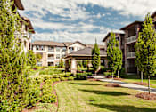 Thumbnail 14 of 18 - A row of apartment buildings with a well-manicured lawn in front.