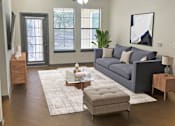 Thumbnail 15 of 36 - A living room with a grey couch, a coffee table, and a ceiling fan.