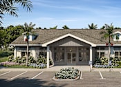 Thumbnail 1 of 7 - A building with a parking lot in front of it.