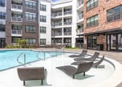 Thumbnail 22 of 25 - a swimming pool with chairs in front of an apartment building