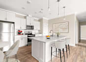 Thumbnail 15 of 43 - A modern kitchen with a white island and bar stools.