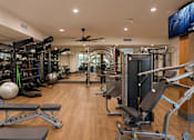 Thumbnail 17 of 40 - A spacious gym with a variety of equipment and a flat screen TV mounted on the wall.