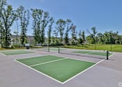 Thumbnail 31 of 49 - A tennis court surrounded by trees and a fence.