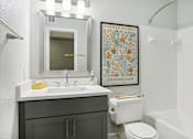 Thumbnail 21 of 28 - A bathroom with a toilet, sink, and poster.
