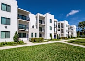 Thumbnail 69 of 78 - A row of white apartment buildings with green lawns in front.
