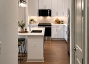 Thumbnail 26 of 40 - A kitchen with white cabinets and a wooden floor.