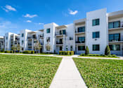 Thumbnail 68 of 78 - A row of white apartment buildings with green lawns in front.