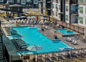 Thumbnail 61 of 94 - a swimming pool at an apartment complex with chairs and umbrellas