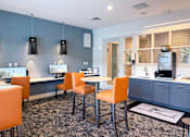 Thumbnail 13 of 31 - A modern kitchen with orange chairs and a grey cabinet.