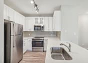 Thumbnail 23 of 36 - A modern kitchen with white cabinets and stainless steel appliances.