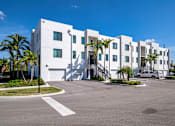 Thumbnail 65 of 78 - A white building with a car parked in front.