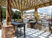 Thumbnail 31 of 46 - Three BR Apartments in Norcross, GA - The Darnell - Covered Grill Area with Two BBQs, Counter Space, and Bar Table with Stools