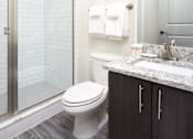 Thumbnail 22 of 25 - A white toilet sits in a bathroom next to a sink.
