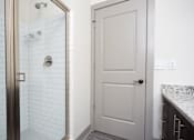 Thumbnail 17 of 25 - A white door is in a bathroom with a marble counter.