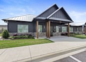 Thumbnail 30 of 53 - the front of a gray building with a porch and a sidewalk