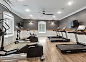 Thumbnail 11 of 53 - a gym with treadmills and weights and a tv