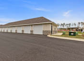 Thumbnail 26 of 53 - a building with white garage doors on the side of a road