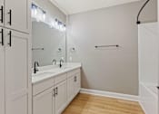 Thumbnail 46 of 53 - a bathroom with two sinks and a shower and white cabinets