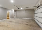 Thumbnail 52 of 53 - an empty basement with a garage door and a ceiling fan
